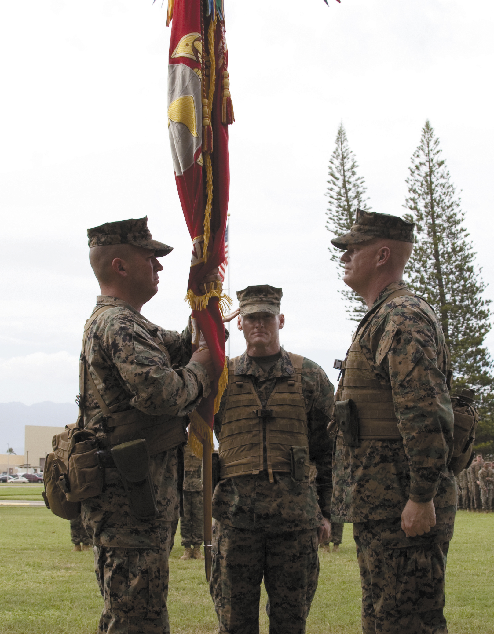 Col. James Bierman (left) receives the colors and assumes command of 3rd Marine Regiment from Col. Duffy White (right) during a change of command ceremony while Sgt. Maj. Paul McKenna, regimental sergeant major, salutes 